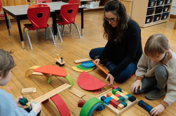 L'adulte joue au sol avec les enfants et sert d'exemple