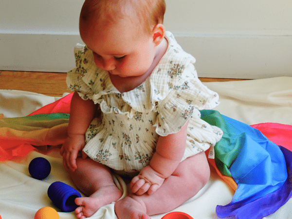 Installer le bébé assis au sol avec des jouets placés près de lui l'invitera à les attraper et à les manipuler